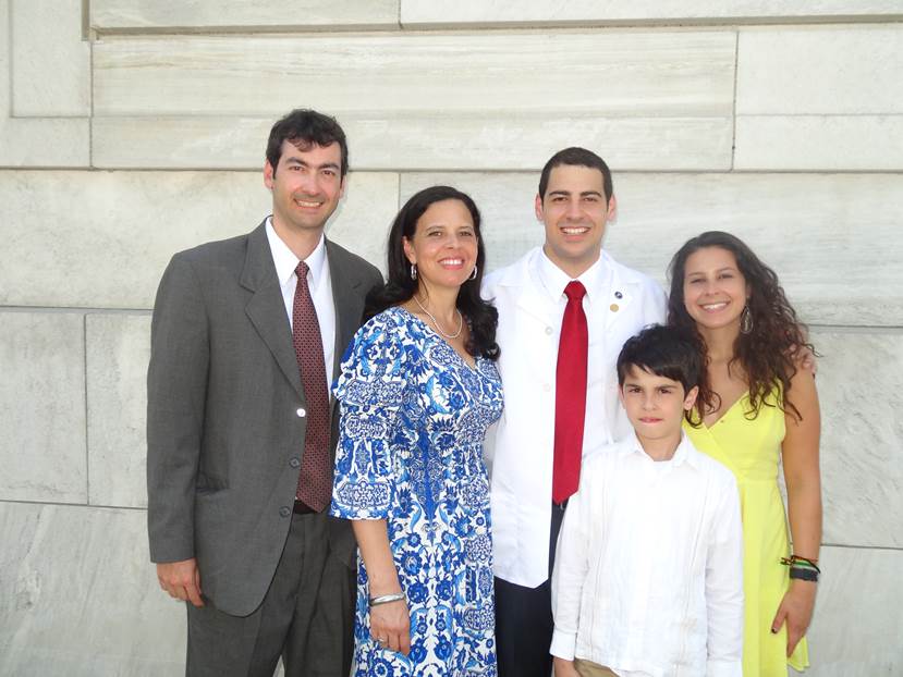 Madison College graduate Camilo Campo stands with his family in his Harvard Medical School white coat.